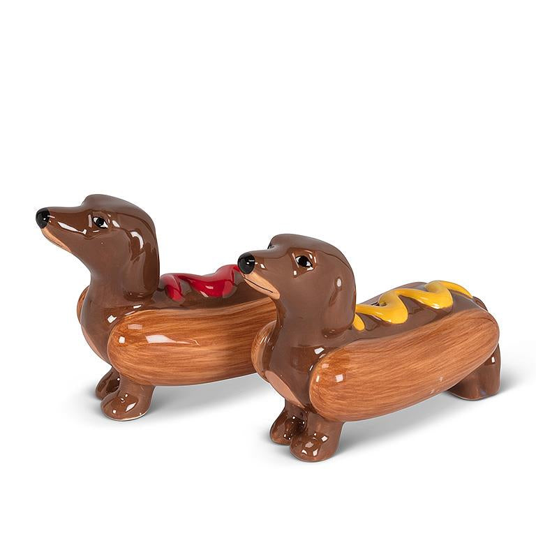 A ceramic salt and pepper set shaped like dachshunds inside hot dog buns, with ketchup and mustard decorations.