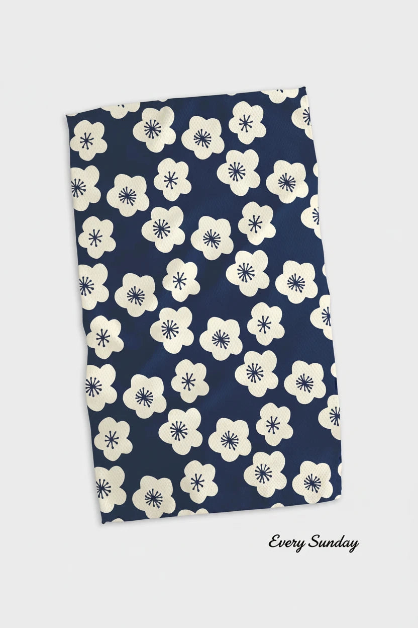 A blue  Geometry every sunday  kitchen tea towel with a white floral pattern.
