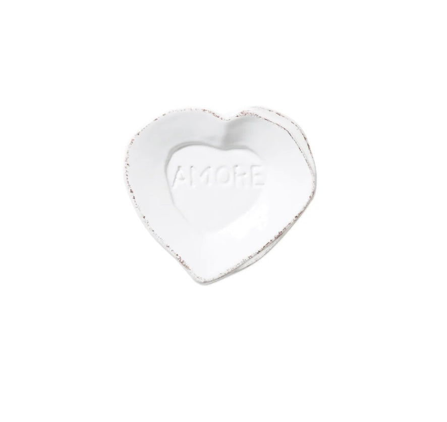 A small white ceramic heart-shaped plate with the word 'AMORE' embossed in the center.