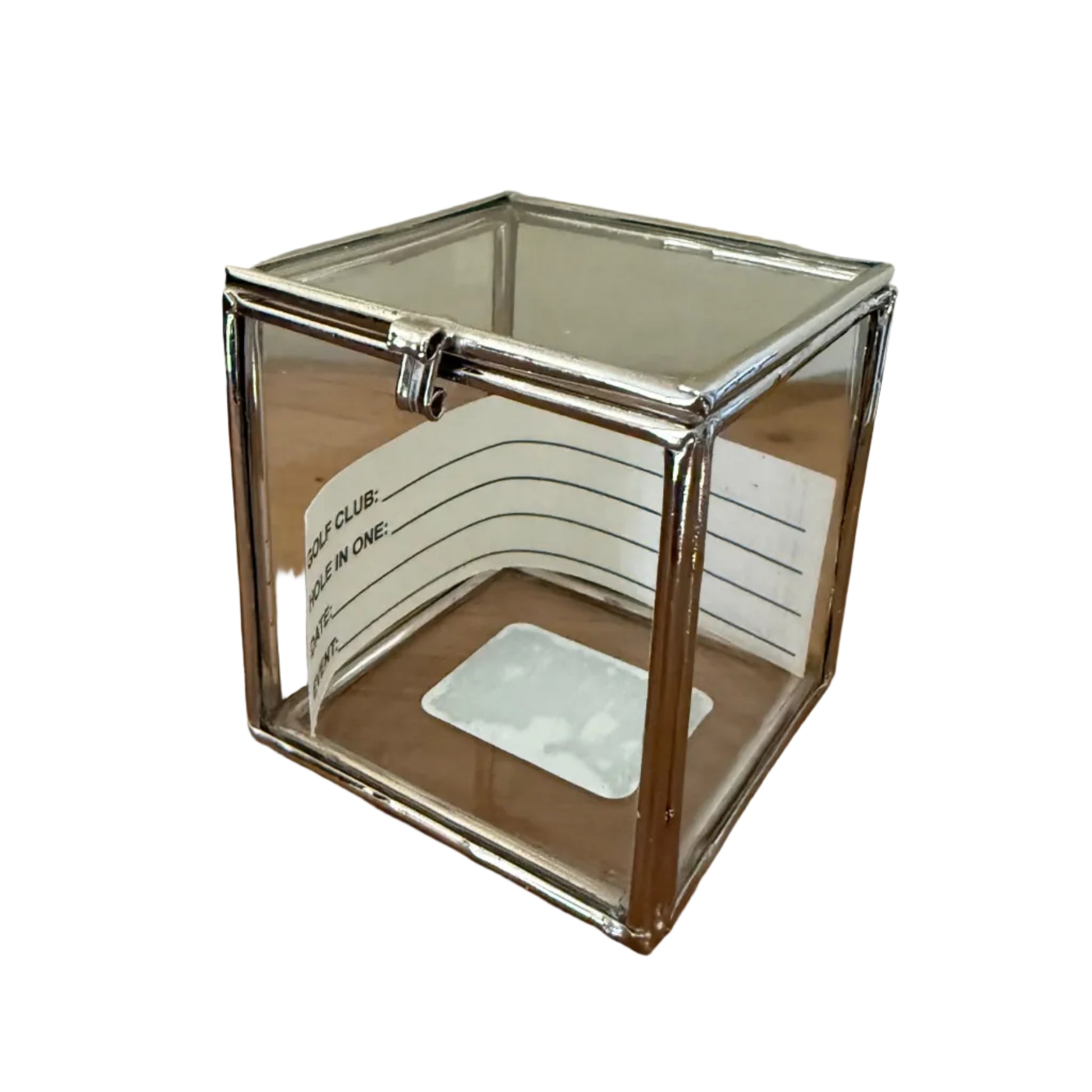 Clear glass hexagonal golf ball display case on a wooden surface with a white wall background