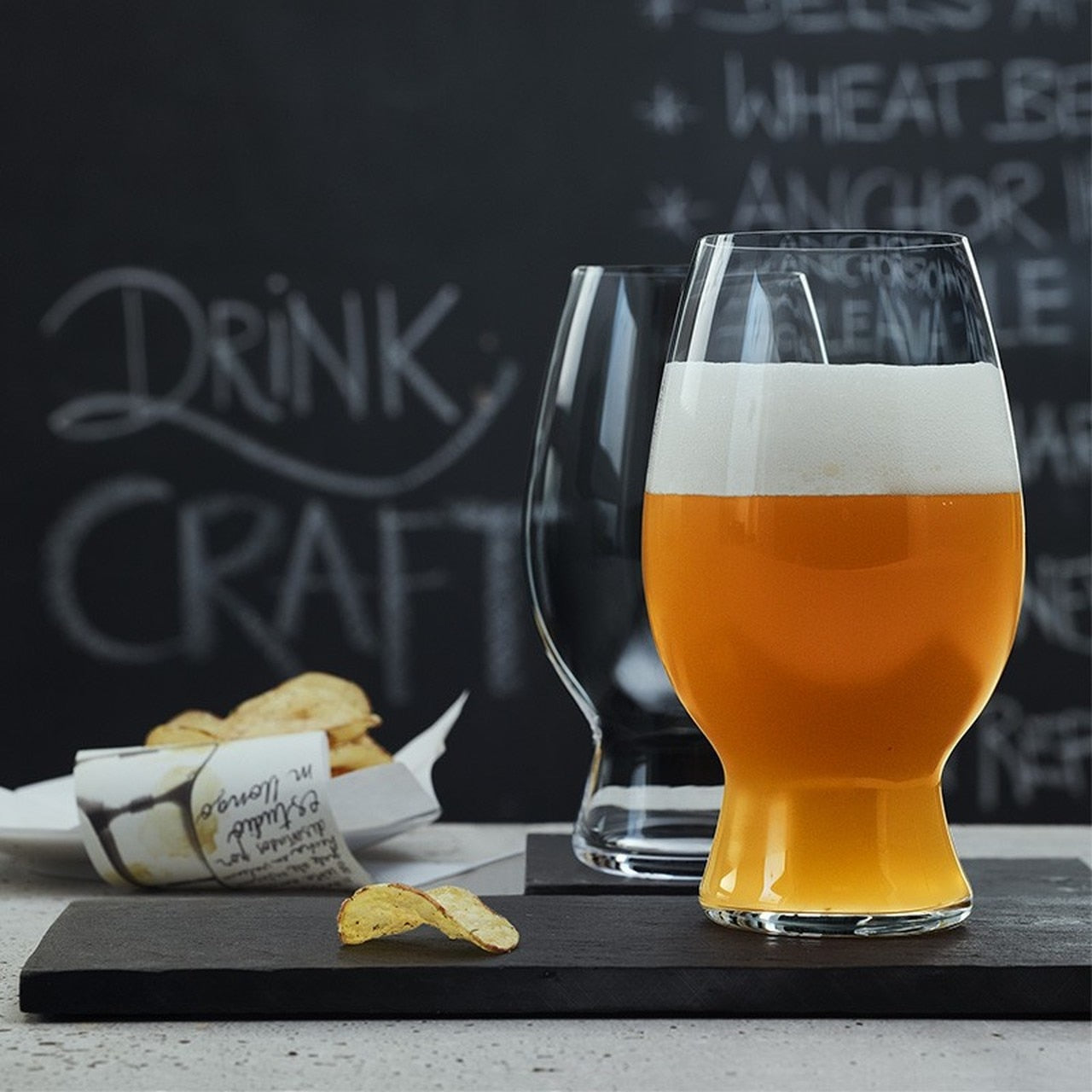 A wheat beer glass filled with beer, showcasing a clear glass with a sturdy base and a slightly flared bowl.