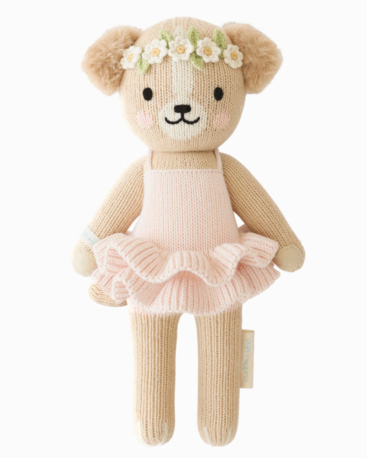 Knitted puppy in a pink tutu dress with a flower crown on a white background