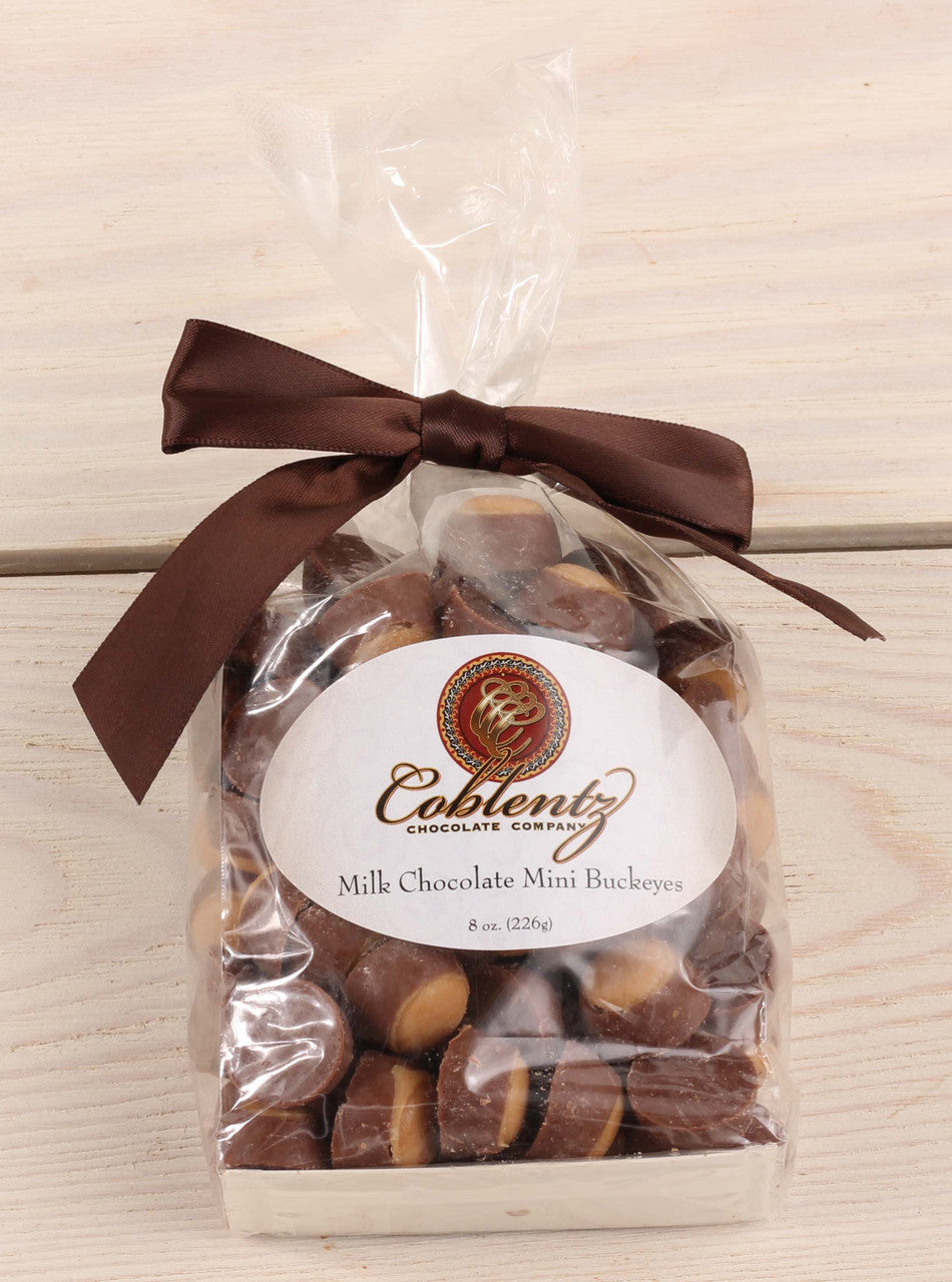 Bag of Coblentz Chocolate Company milk chocolate mini buckeyes with a brown ribbon on a wooden surface.