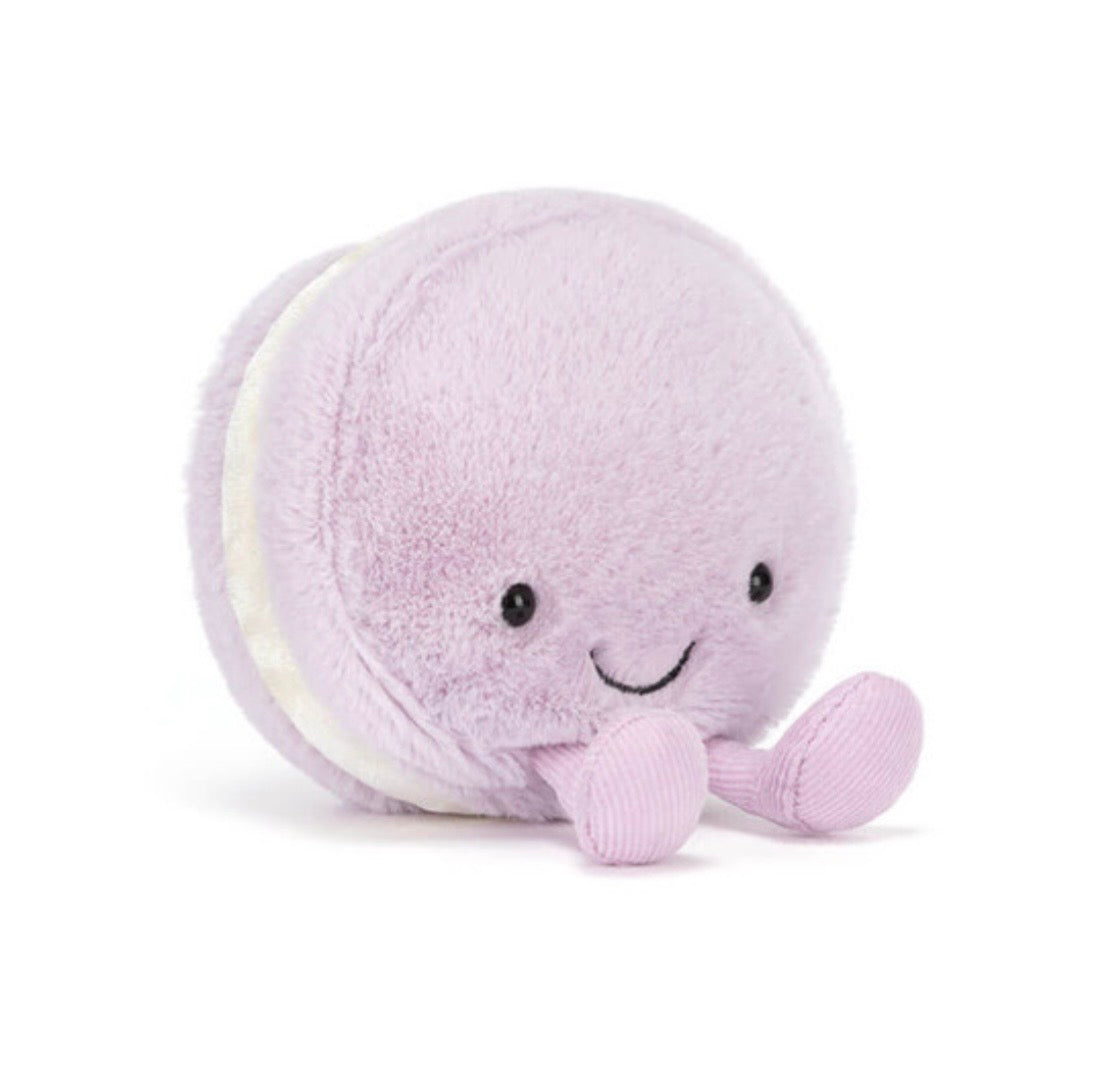 Plush toy resembling a purple macaron with a smiling face on a white background