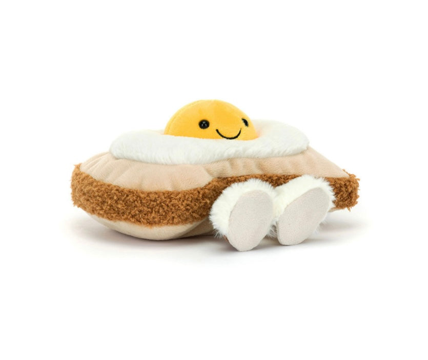 A plush toy resembling an egg on toast with a smiling yolk face, fluffy white slippers, and a brown toasted bread slice.
