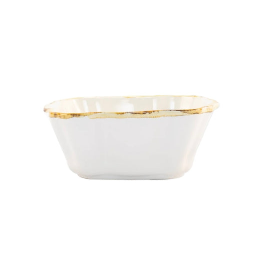 A small square white ceramic baker with scalloped edges and a rustic brown rim.