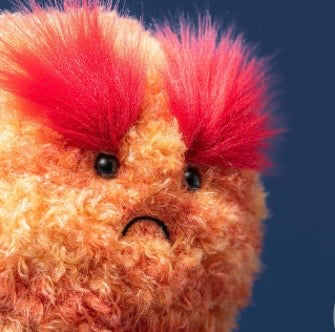 Plush toy with a sad expression and red hair against a dark blue background