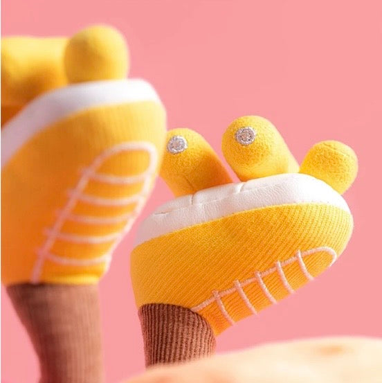 Yellow baby socks with white soles on a pink background