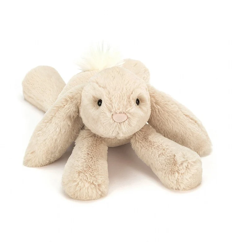 A beige plush toy rabbit with long ears, lying down on a plain background.
