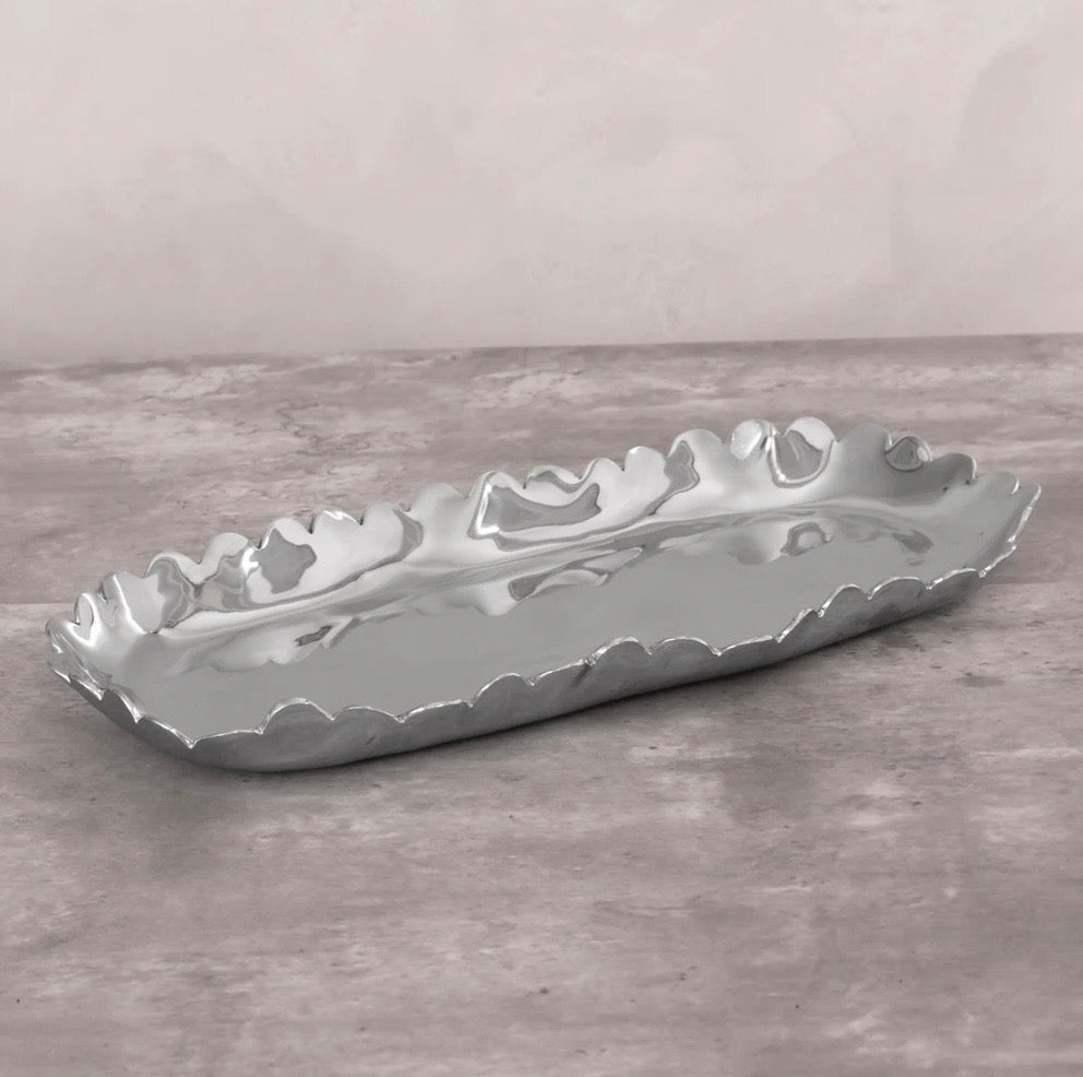 Decorative gray ceramic tray with wavy edge on a gray surface