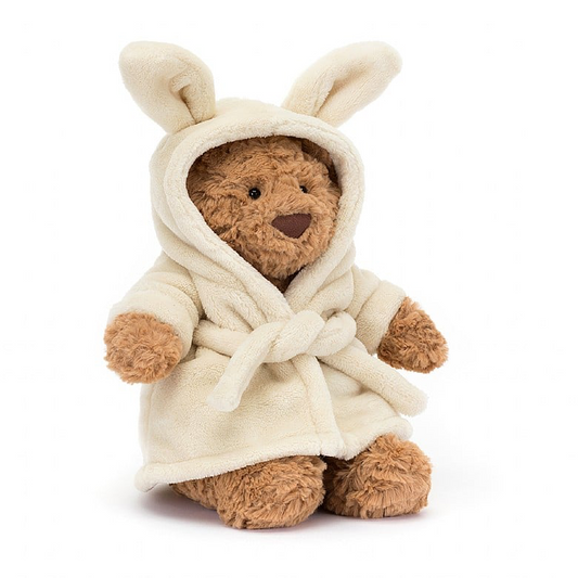 A plush bear wearing a beige bathrobe with bunny ears.