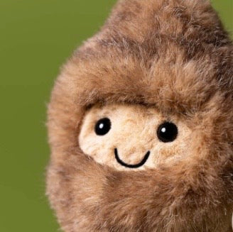 Plush toy resembling a character with a brown fur-like texture on a green background