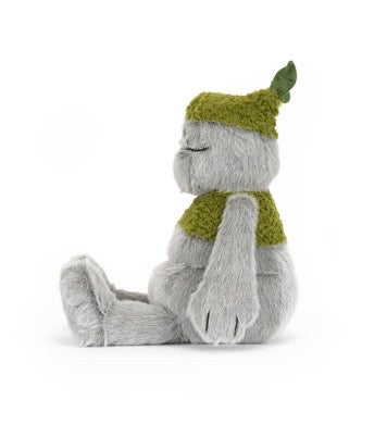 Plush toy resembling a creature with a green hat and scarf on a white background