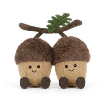Two knitted acorn toys with faces and a twig on a white background