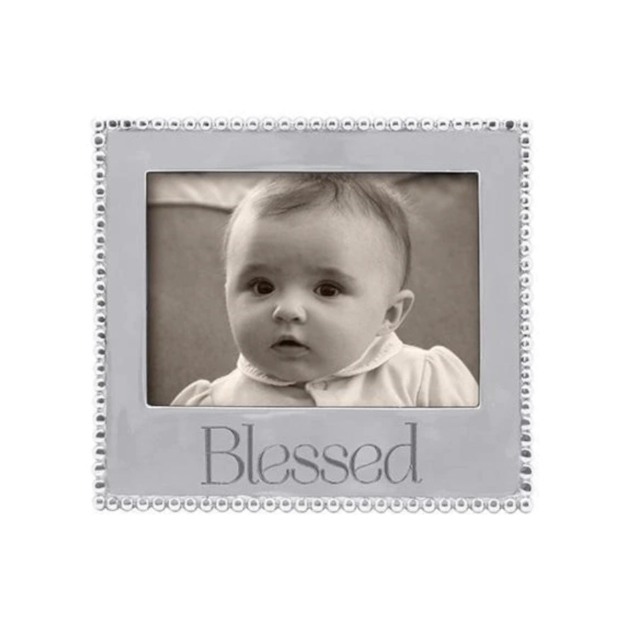 A 5x7 picture frame with a beaded design and the word 'Blessed' printed on the front, containing a photo of a baby.
