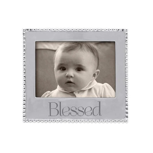 A 5x7 picture frame with a beaded design and the word 'Blessed' printed on the front, containing a photo of a baby.