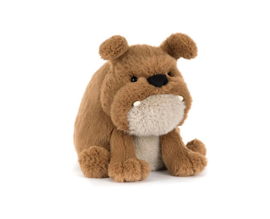A soft brown plush toy resembling a bulldog with a grumpy facial expression, featuring stitched details for eyebrows and a mouth, and a cream-colored nose and mouth area.