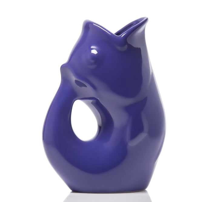 Indigo blue ceramic pitcher shaped like a fish on a white background