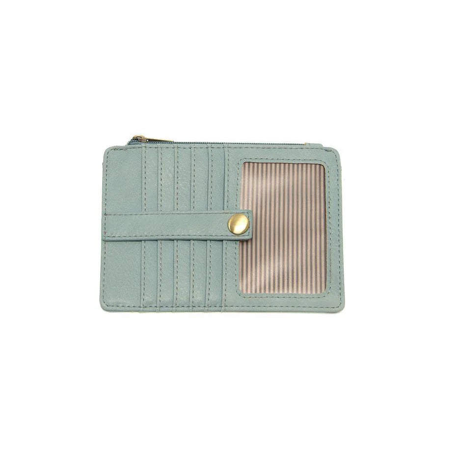 A blue sugar vegan leather mini travel wallet with a top zip closure, multiple card pockets, an ID window pocket, and an exterior passport pocket. It has brass plated hardware and is slim enough for travel use.