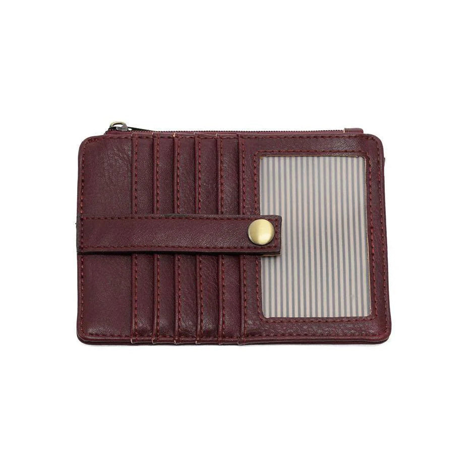 A blackberry vegan leather mini travel wallet with a top zip closure, multiple card pockets, an ID window pocket, and an exterior passport pocket. It has brass plated hardware and is slim enough for travel use.
