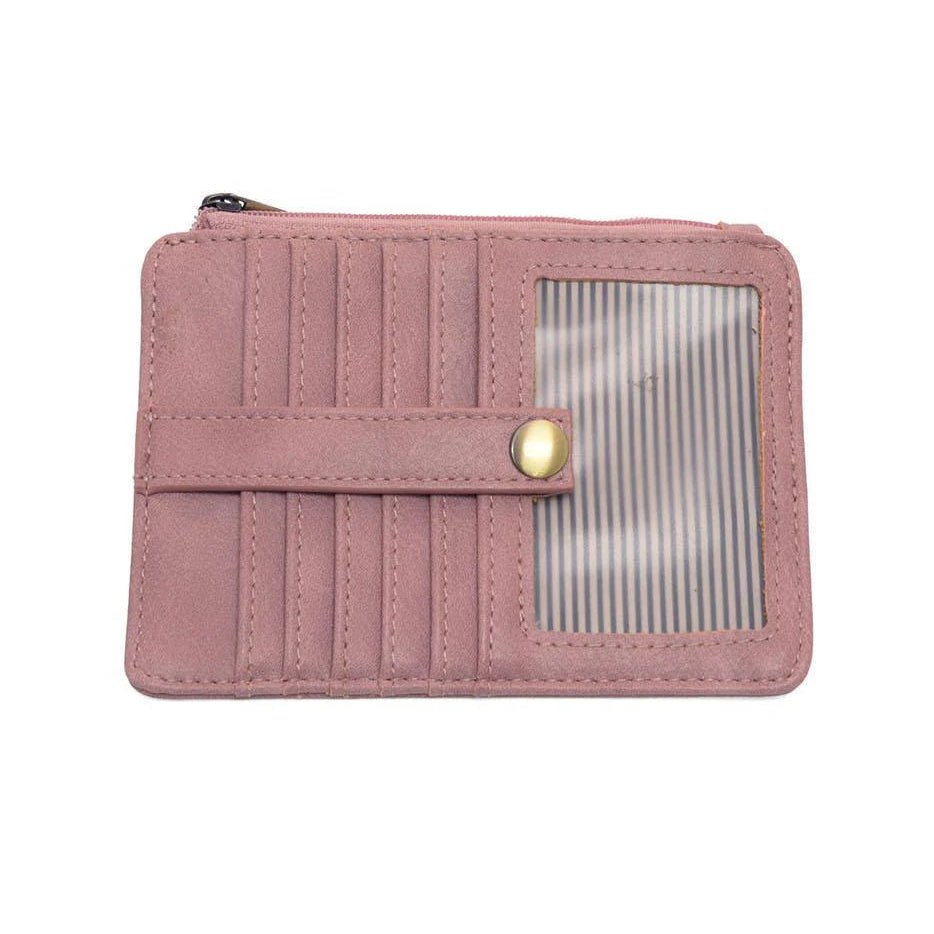 A soft berry vegan leather mini travel wallet with a top zip closure, multiple card pockets, an ID window pocket, and an exterior passport pocket. It has brass plated hardware and is slim enough for travel use.
