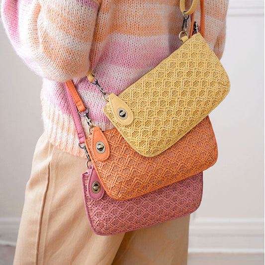Three woven handbags, one pink, one coral and one yellow, being carried by a person wearing a plaid sweater.