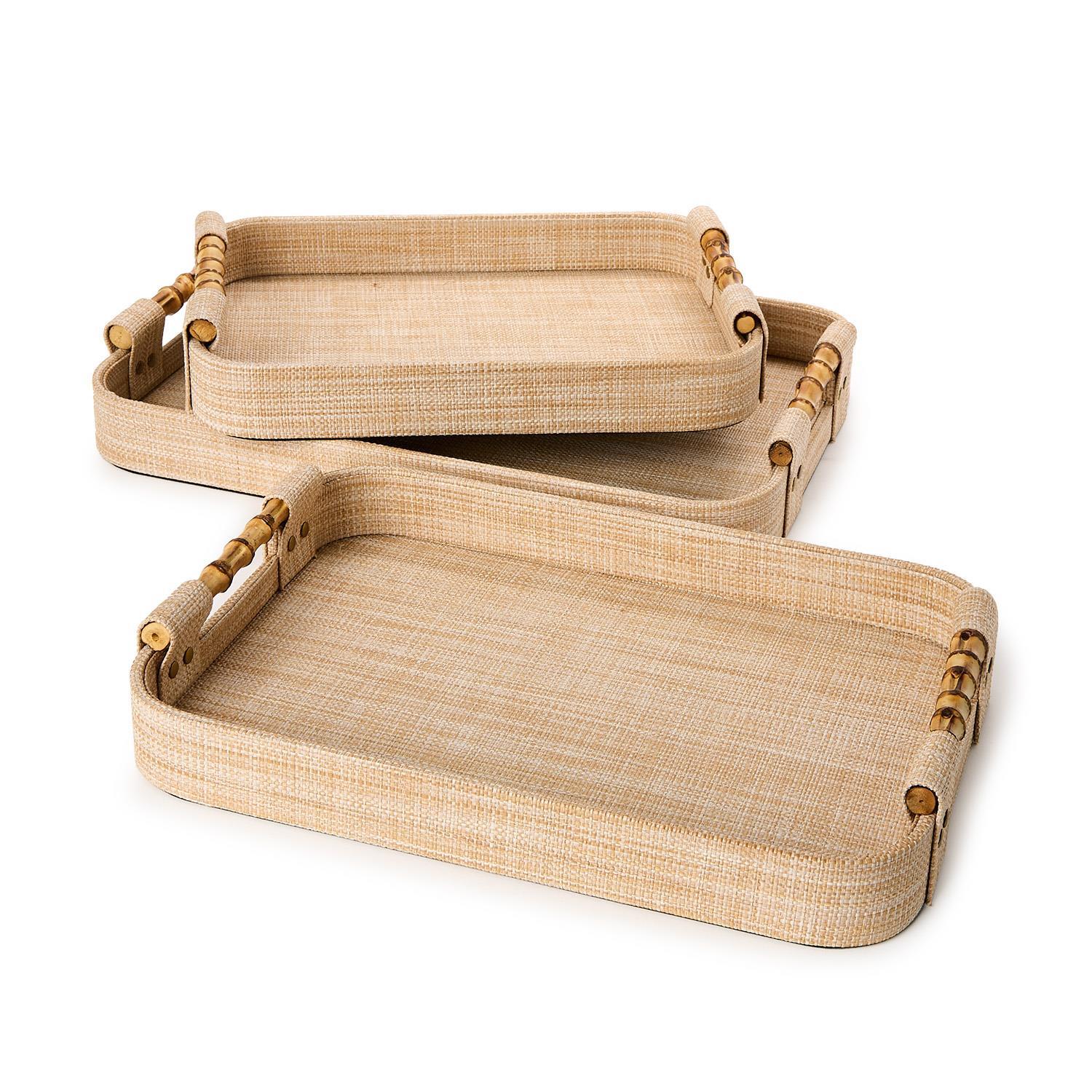 Three woven rattan trays with bamboo handles on a white background
