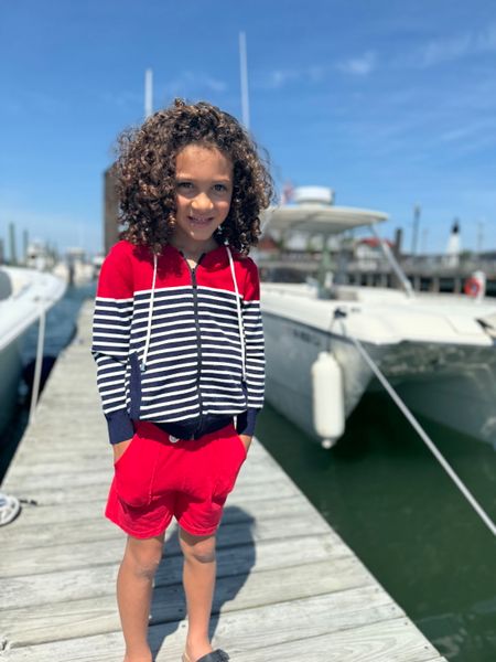 Child wearing a Me and Henry Sagamore Red/White Stripe Zip Up Hoodie standing on a boat dock