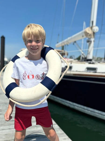 Child holding a life buoy with a sailboat in the background wearing a Me & Henry nautical Falmouth t-shirt
