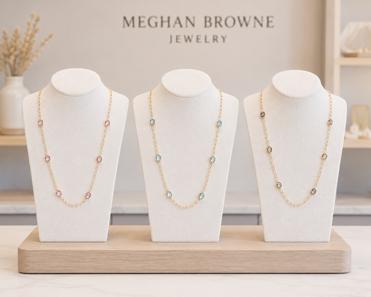 Three Meghan Browne FUGI necklaces each with gold link chains and stationary stones in pink mint and clear in a meghan browne jewelry store