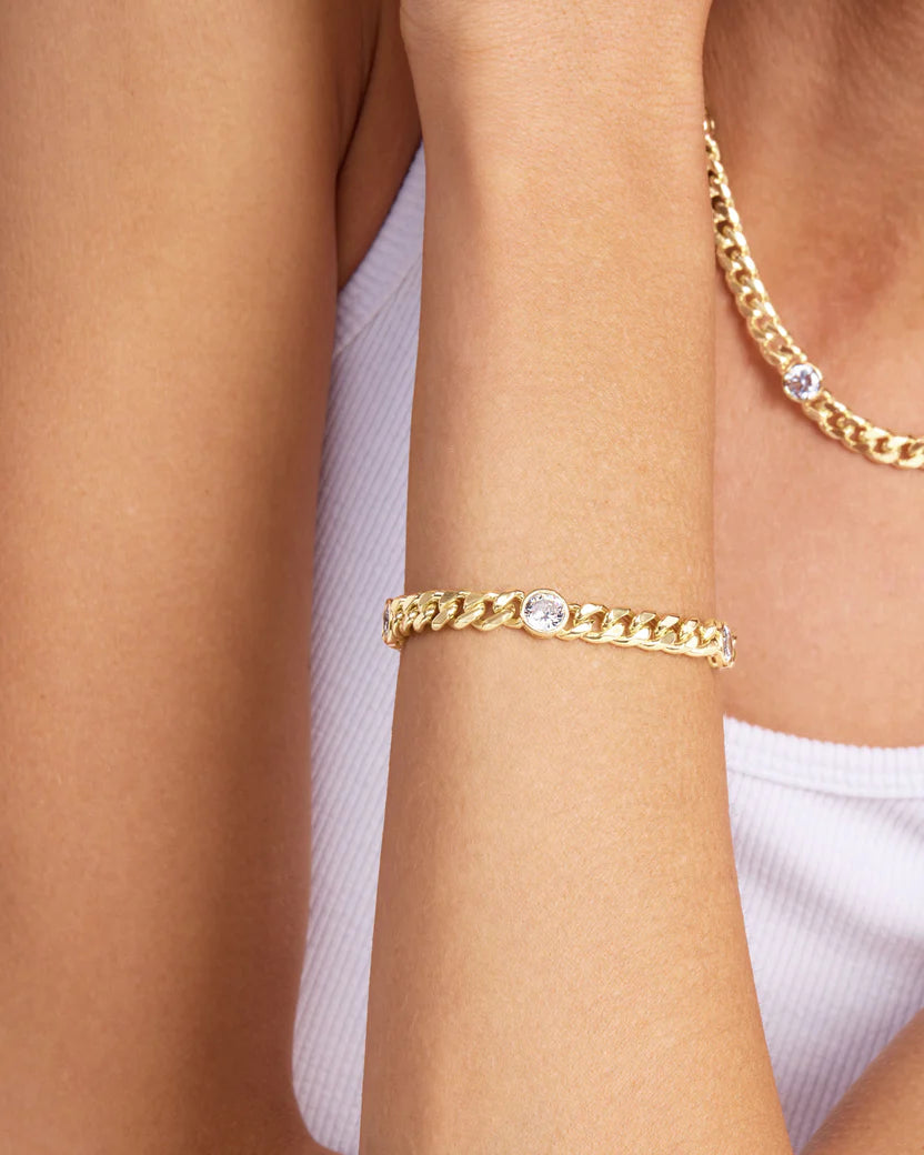 Melinda Maria Julian Triple Diamond Cuban Gold Bracelet on a person's wrist against a neutral background