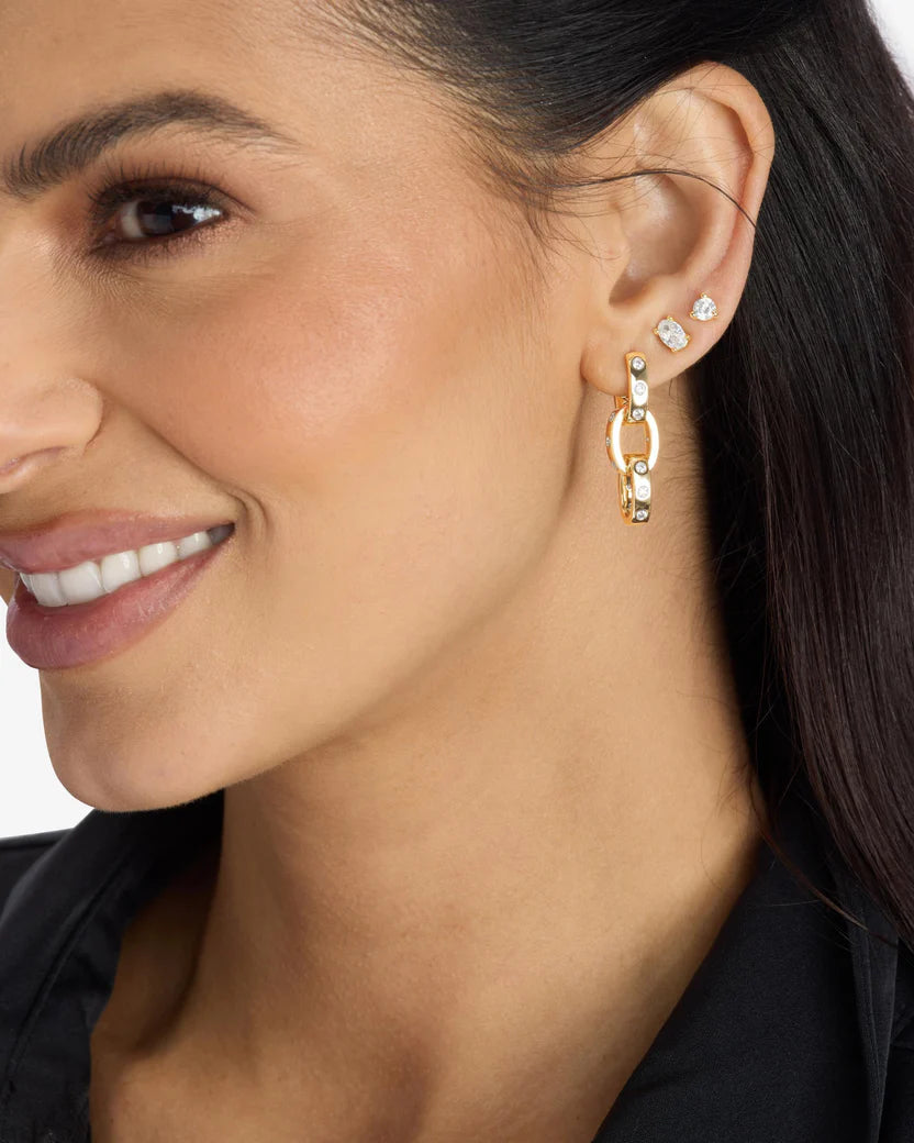 Close-up of a woman wearing Melinda Maria Ashley gold hoop link earrings with small gemstones.
