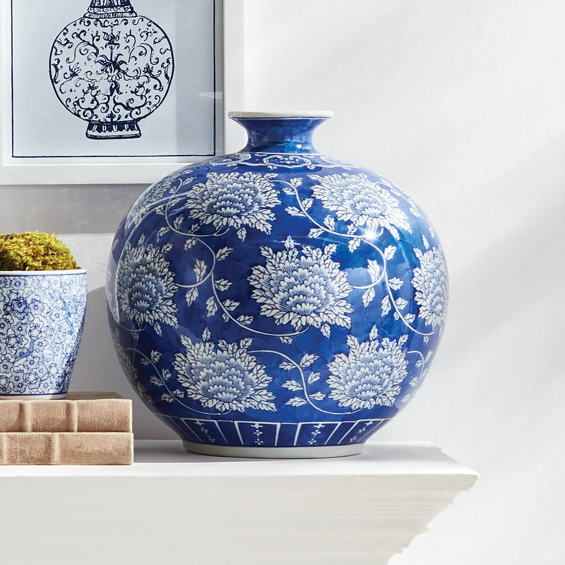 Classic Blue and White Napa Home Barclay Butera Dynasty Tang Vase on a shelf with a framed picture in the background.