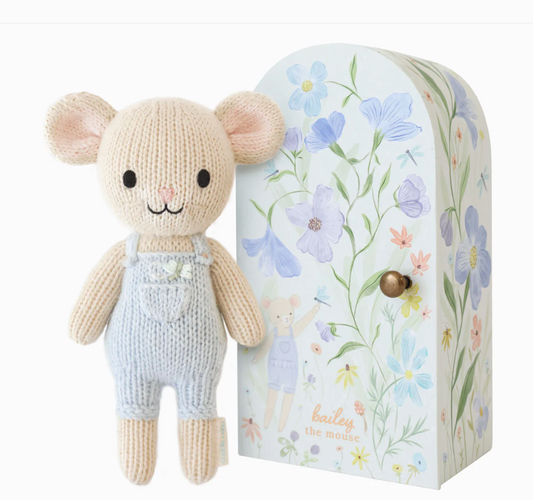 Knitted mouse toy wearing blue coveralls with a floral-patterned box 