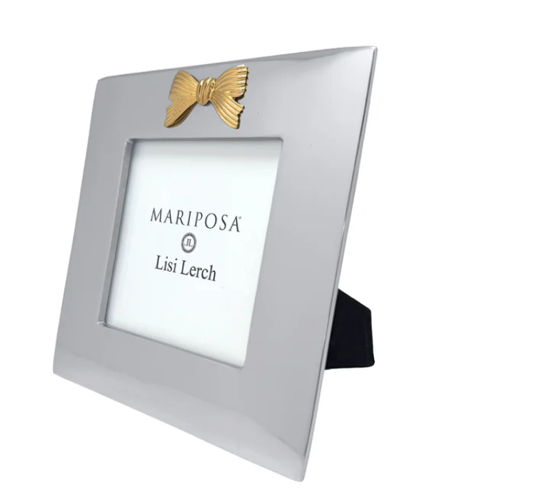 A square silver picture frame with a decorative gold bow at the top and a black stand, shown on a plain white background. The insert card reads 'MARIPOSA Lisi Lerch'.