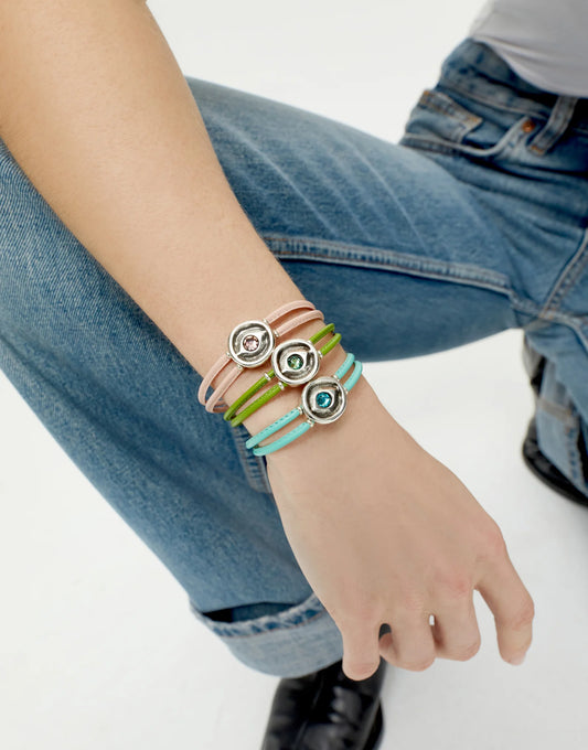 Person wearing multiple UNOde50 Ser Intuitiva colorful bracelets on a plain background