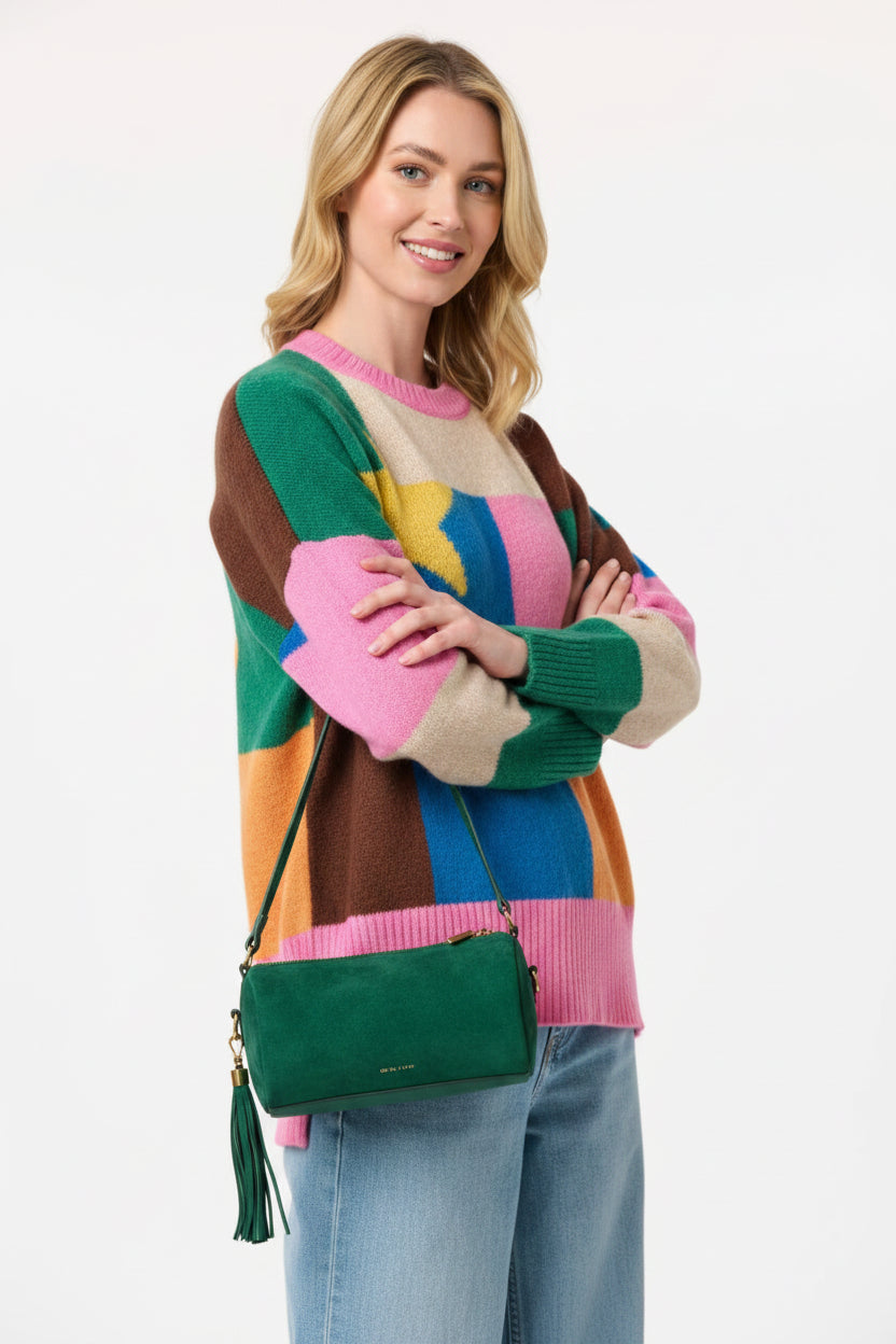 Woman wearing a colorful sweater with a patterned design holding an emerald green Shiraleah Kylie shoulder bag.