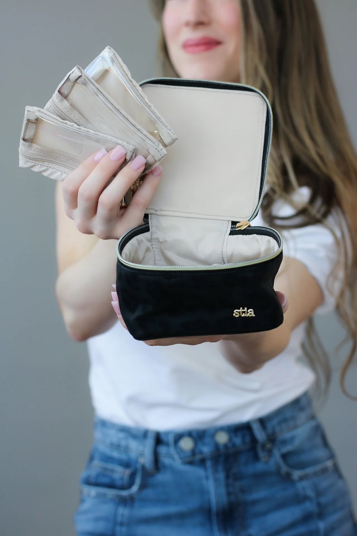 Person holding a stia jewelry travel case with a ring inside against a neutral background