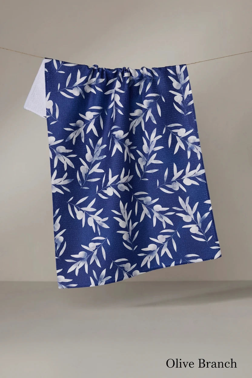 Blue Geometry olive branch tea towel with white leaf pattern hanging on a line against a neutral background