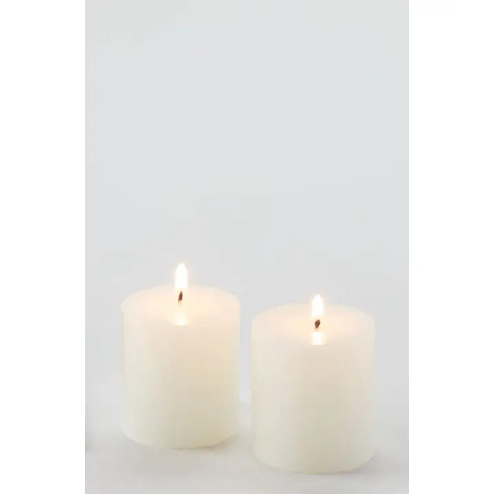 Two white candles on a light gray background