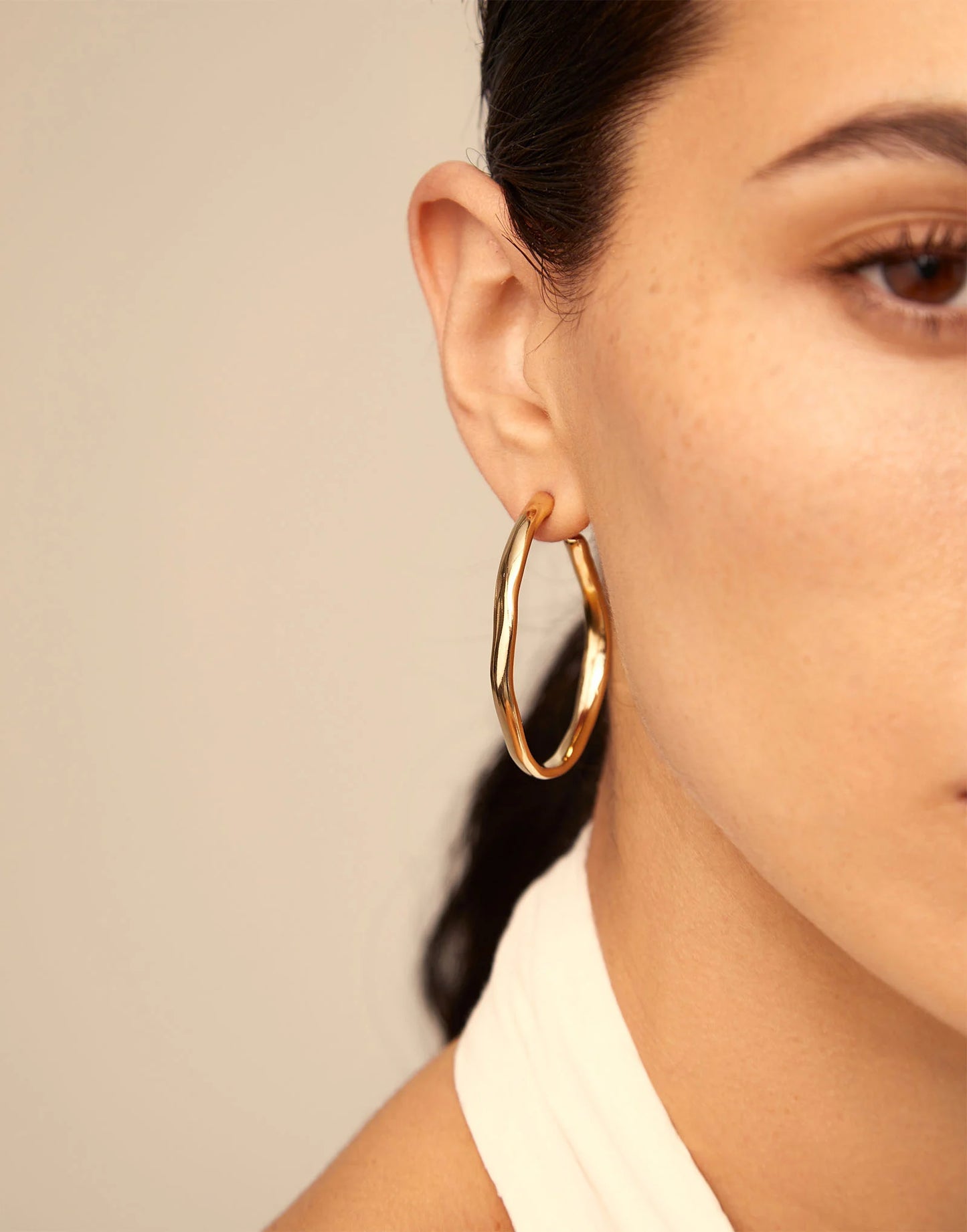 Close up of a woman wearing UNOde50 Ohmmm Gold Bent Open Hoop Earrings