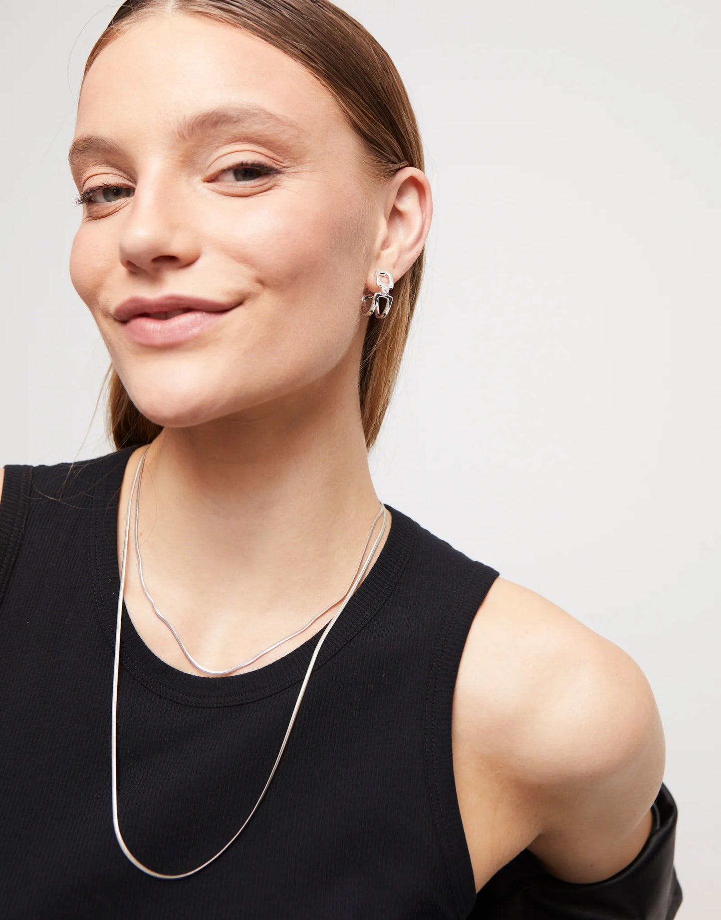Woman wearing black shirt and UNOde50 necklace and  Ser Indomitable Silver Hoop Earrings with White Topaz