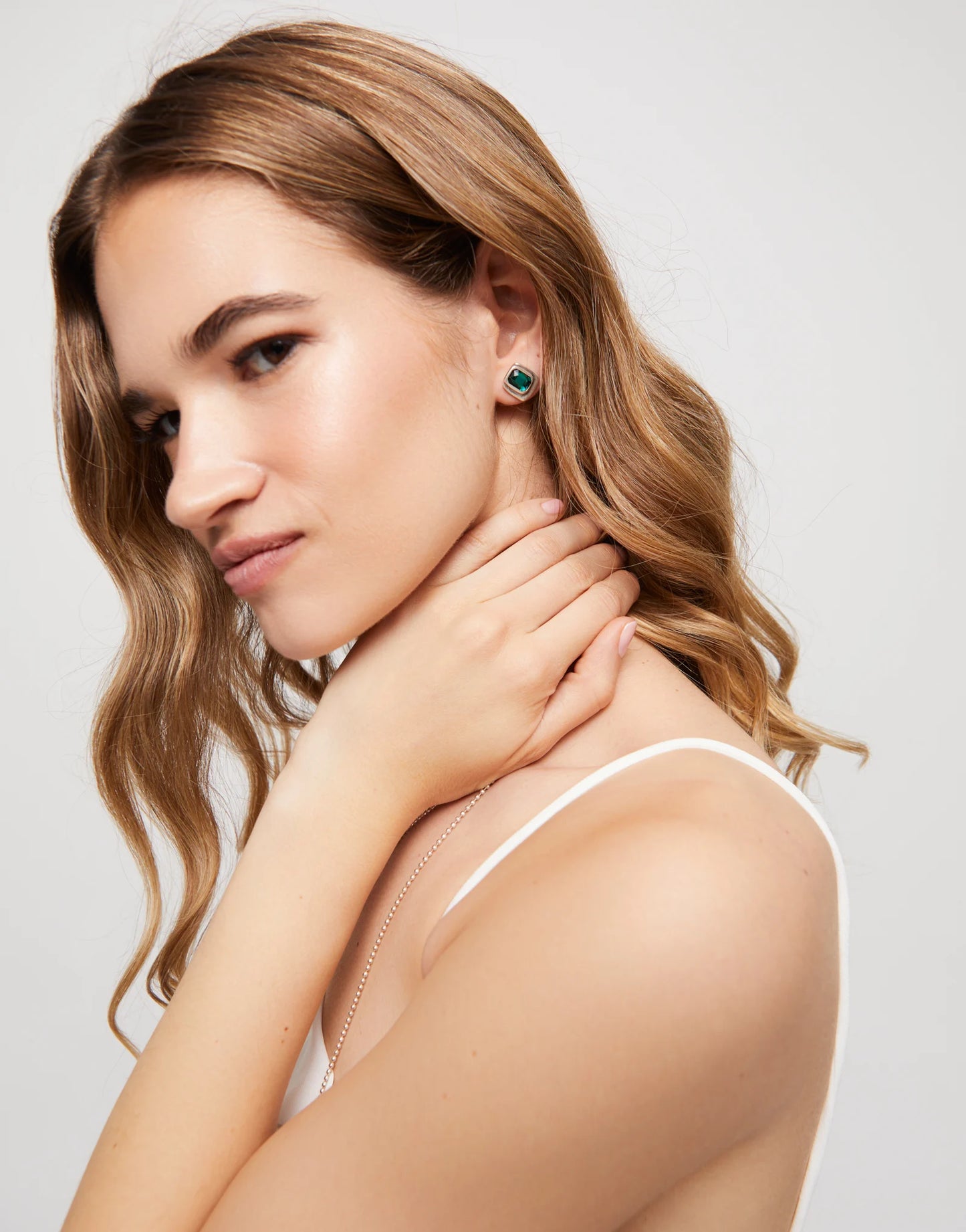 Model wearing UNOde50 Ser Magnetica Silver Earrings with Green Crystal with a white background