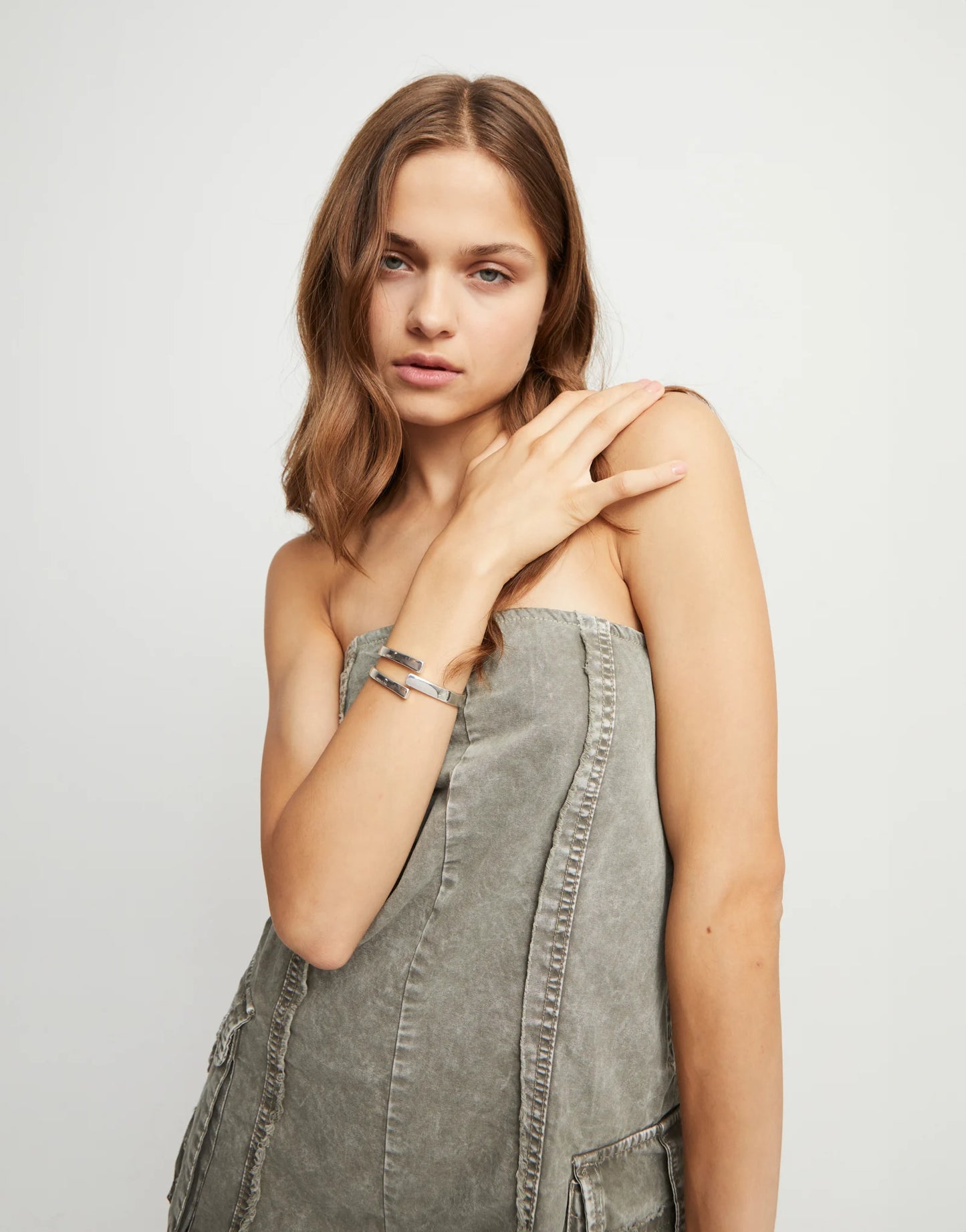 Woman in dress wearing an UNOde50 Ser Original Silver Bangle Bracelet with a neutral background