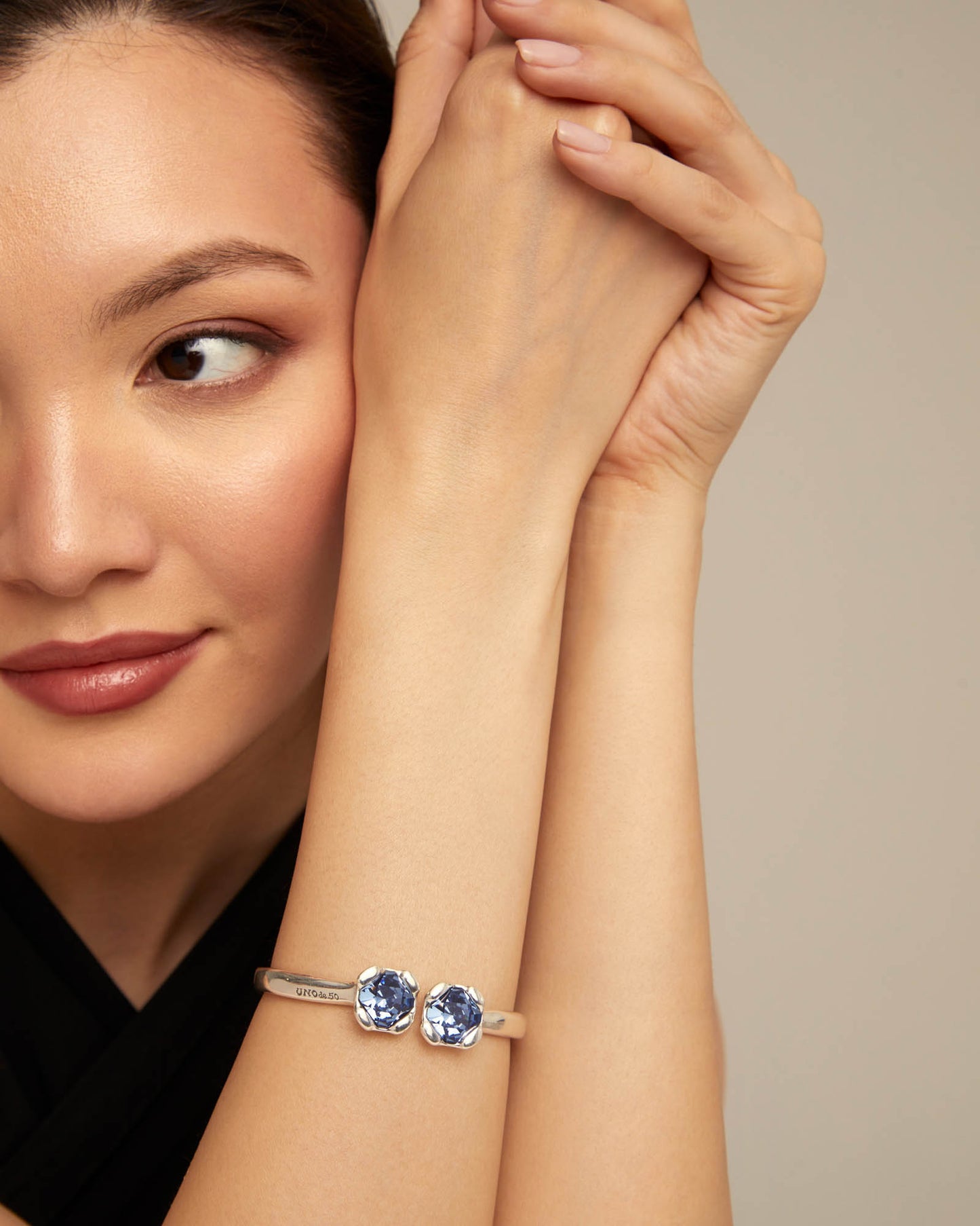 Close up of a woman wearing UNOde50 Aura Blue Silver Bangle Bracelet with two Blue Crystals