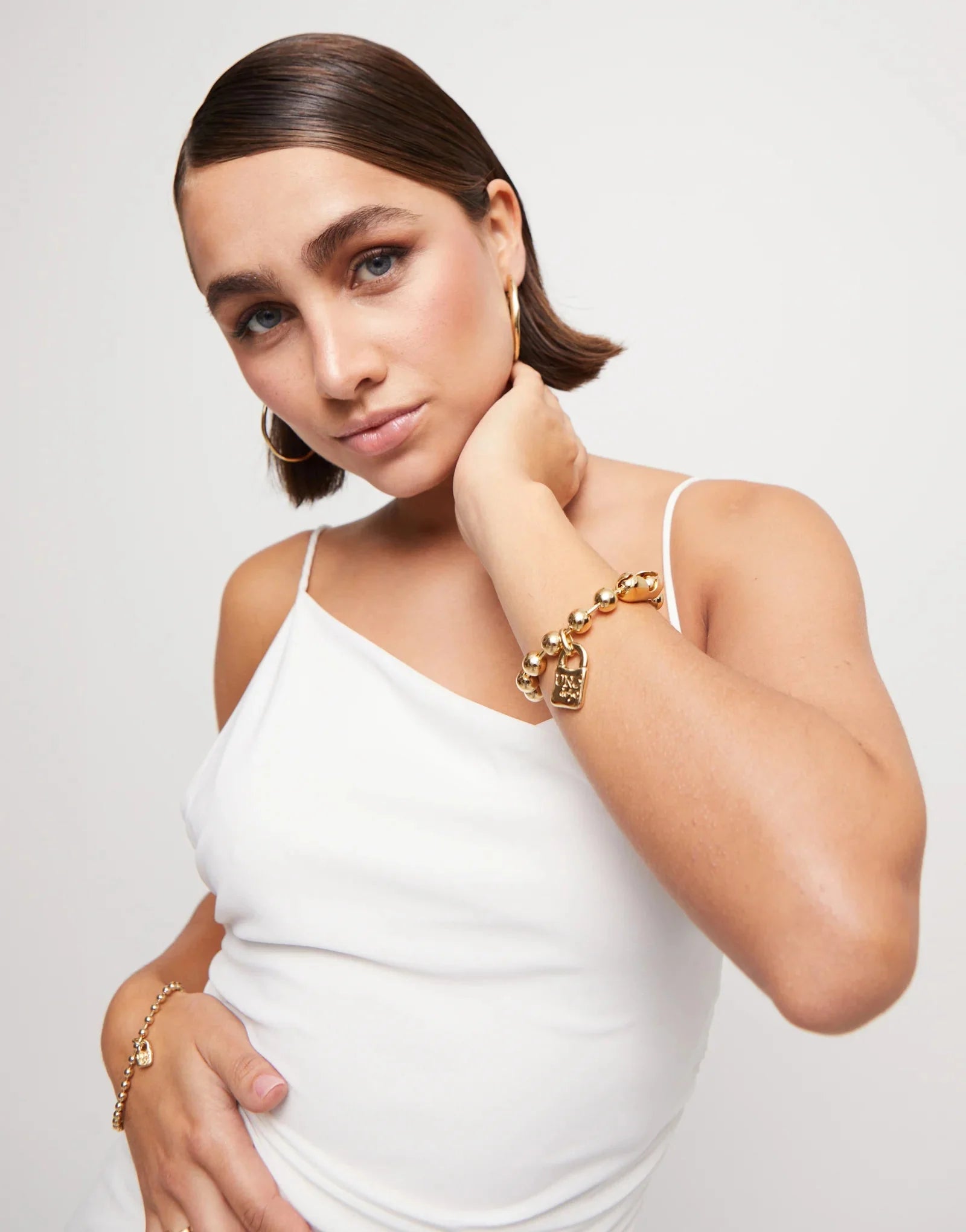Girl in white tank top wearing an UNOde50 Copito de Nieve beaded Gold Bracelet with Padlock