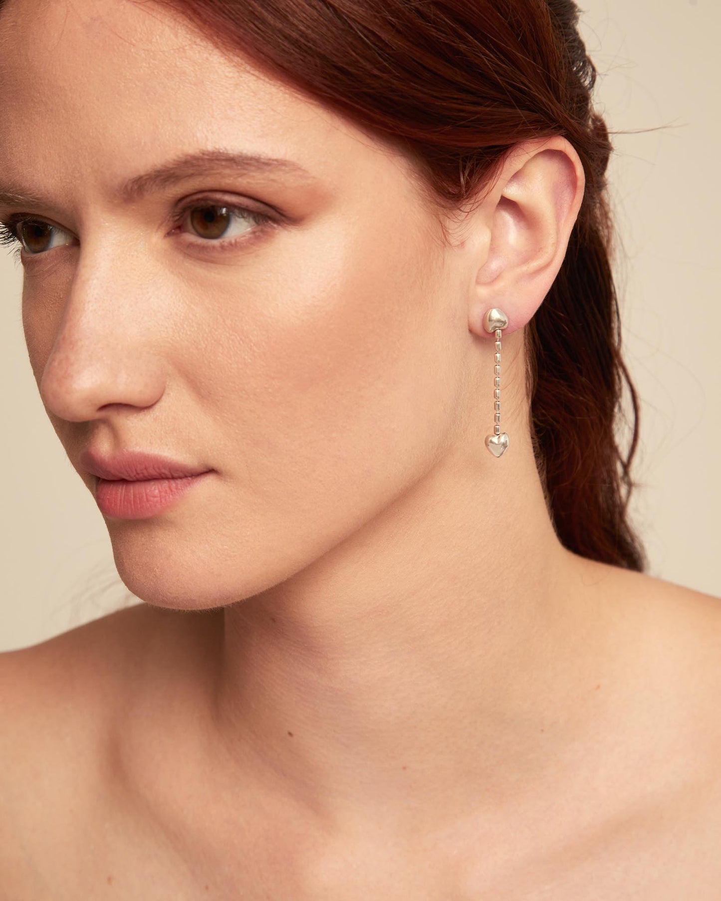 Close up of a woman wearing UNOde50 Cupido Beloved Silver Drop Earrings with a Small Heart