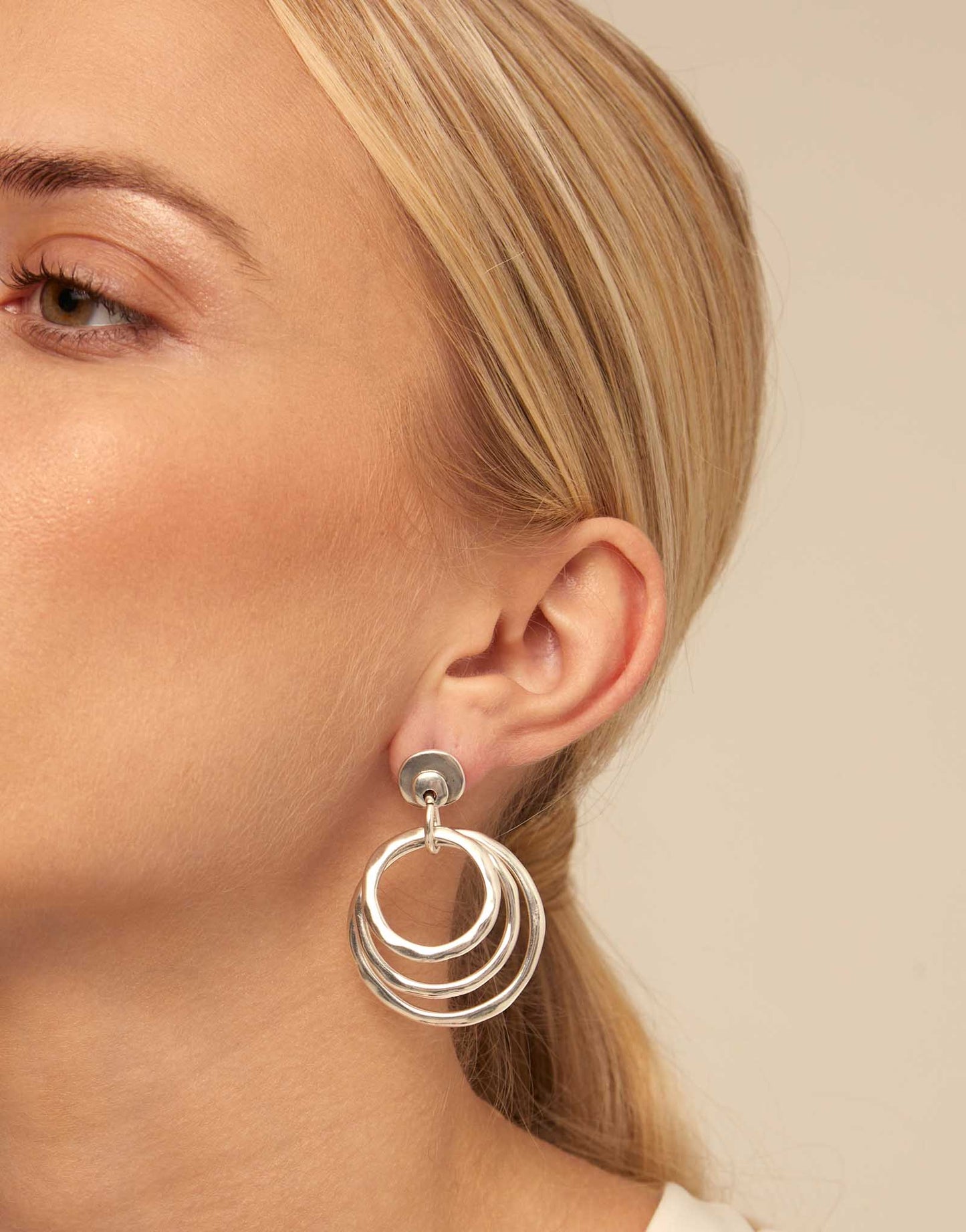 Woman with blonde hair wearing UNOde50 En La Onda Silver Irregular Hoop Earrings