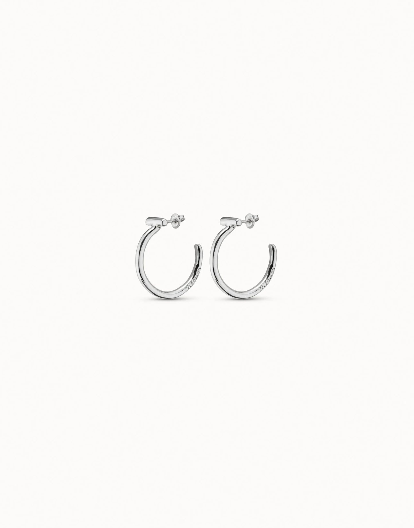 Side view of UNOde50 It's electrifying silver hoop earrings with bar detail on a white background