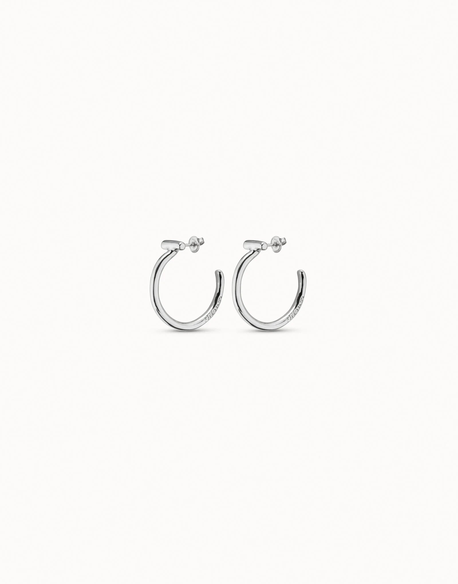 Side view of UNOde50 It's electrifying silver hoop earrings with bar detail on a white background